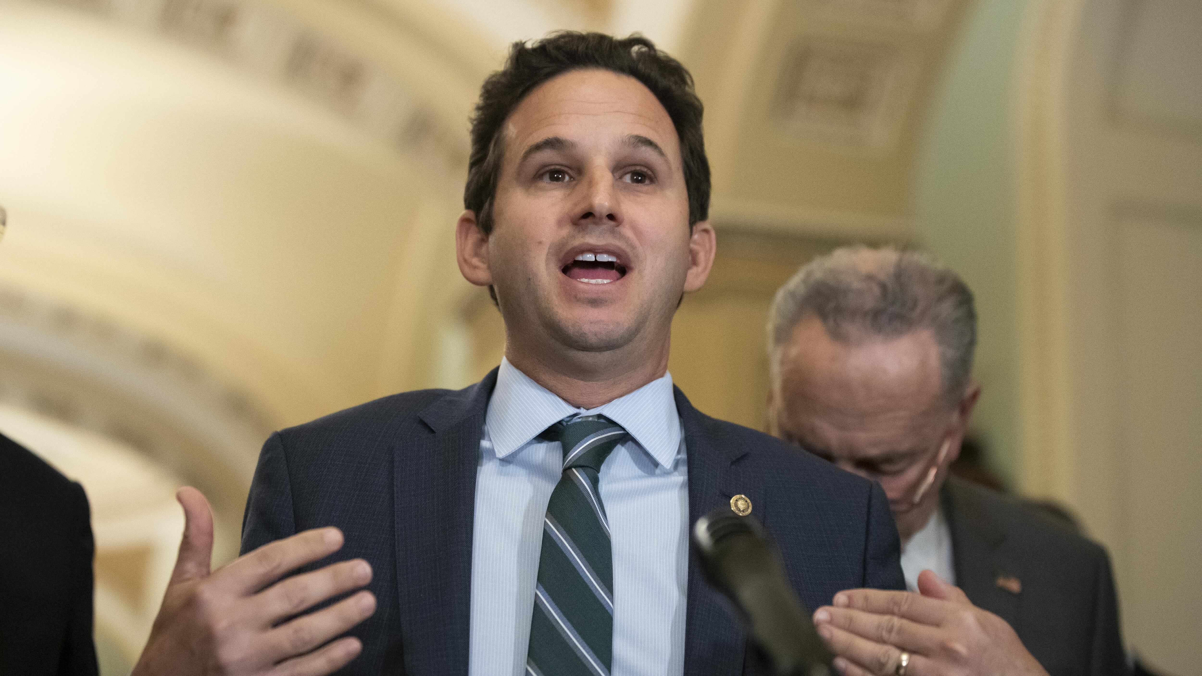 Sen. Brian Schatz stands at a podium.