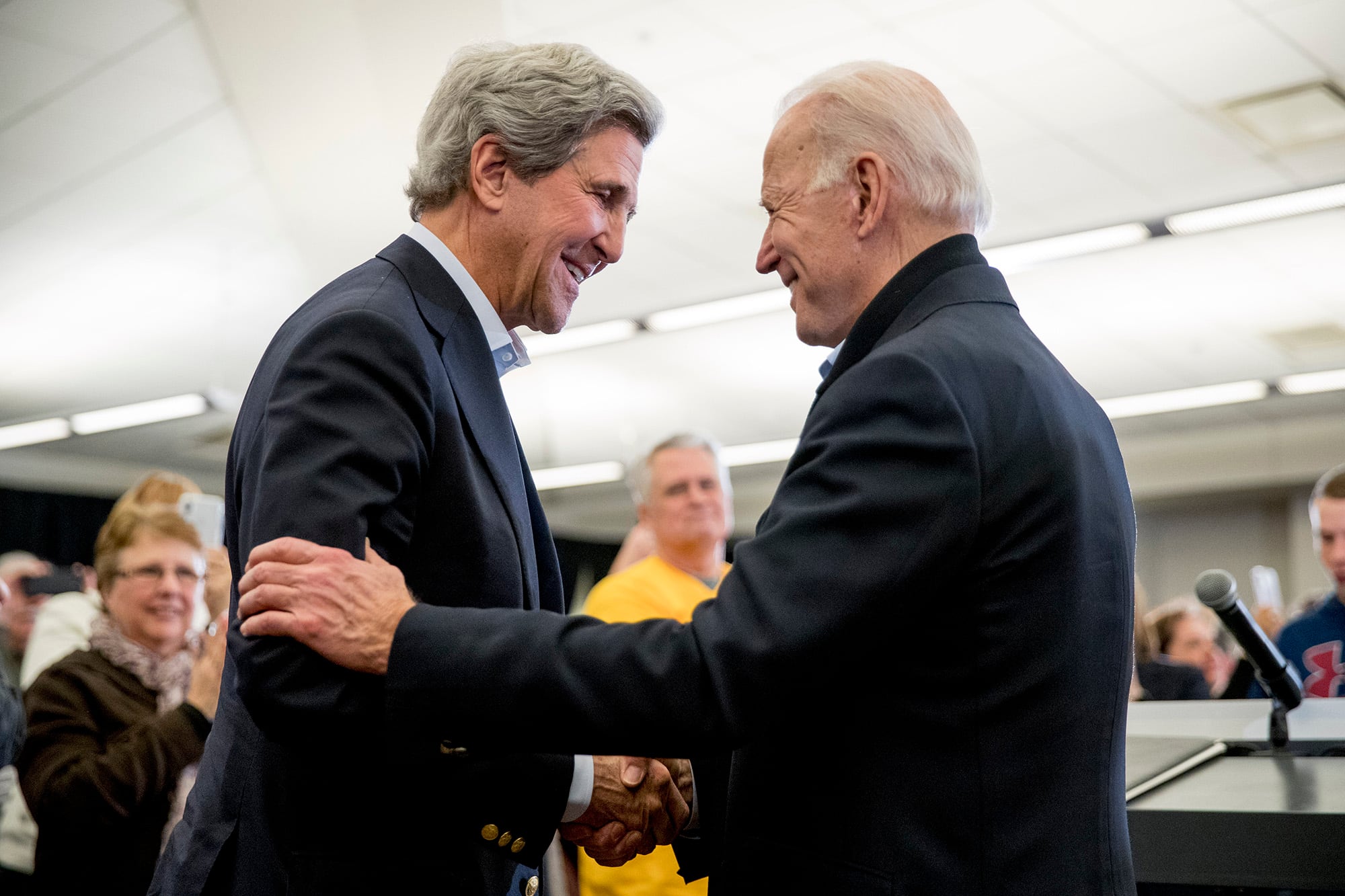 In this Feb. 1, 2020, file photo Democratic presidential candidate former Vice President Joe Biden smiles as former Secretary of State John Kerry, left, takes the podium to speak at a campaign stop at the South Slope Community Center in North Liberty, Iowa.